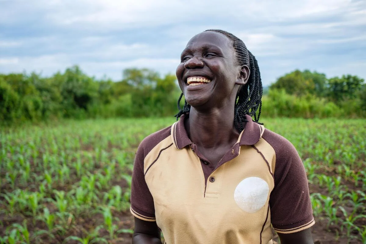 A smiling farmer standing among green crops